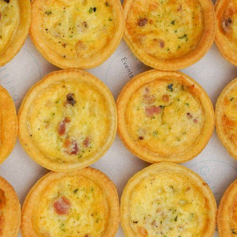 Row of small quiches on a white surface