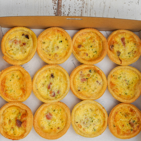 Box of small quiches on a white surface