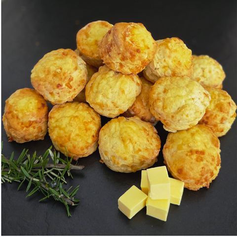 Cheese puffs with butter cubes and rosemary on a dark surface
