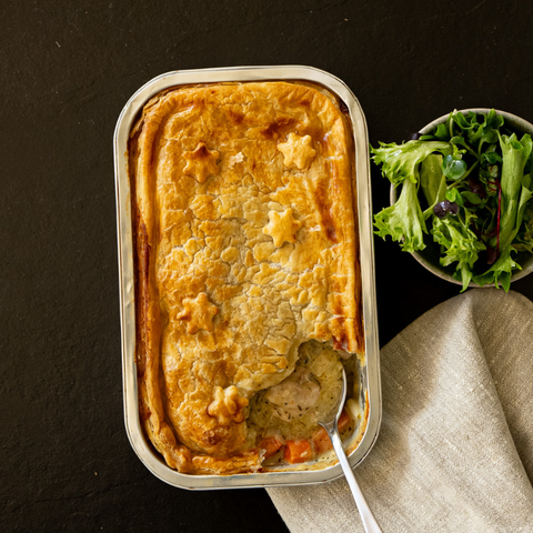 Baked dish in a metal tray with a side of salad on a dark surface