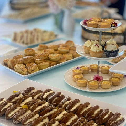 Assorted pastries including tarts, cupcakes, and cookies on a buffet table.