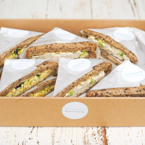 Box of triangular sandwiches on a wooden surface