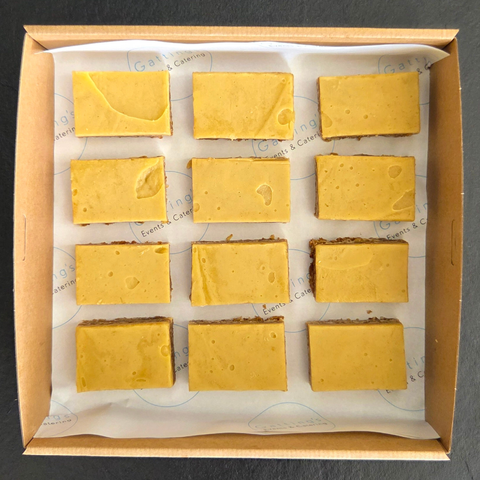Box of yellow fudge squares on a dark background