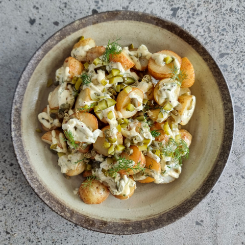 Plated dish of pasta salad with carrots and herbs on a textured surface
