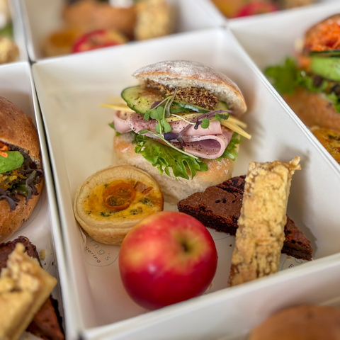Assorted food items including a sandwich, apple, and bread in a box.