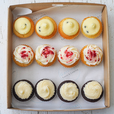 Box of assorted cupcakes with different frosting flavors on a white background