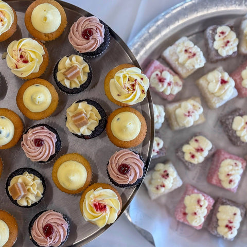 Assorted small cupcakes and cookies on a metal tray.