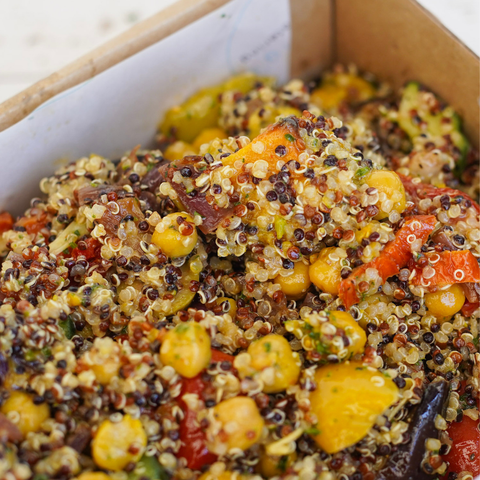 Colorful quinoa salad with vegetables in a cardboard container