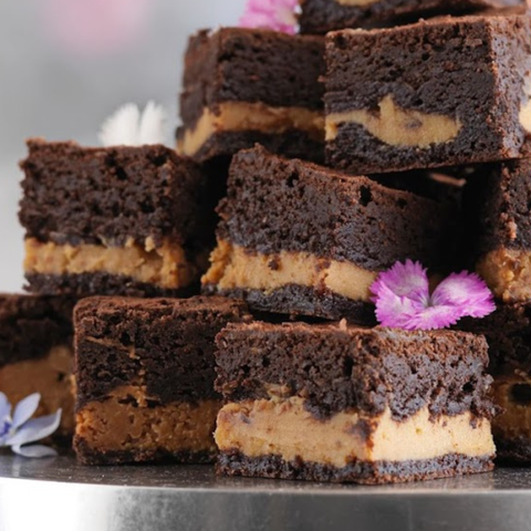 Stack of chocolate brownies with a creamy filling on a metal tray.