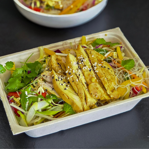 Salad with egg and vegetables in a takeout container on a dark surface