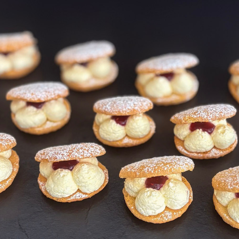 Small pastries with cream and jam filling on a dark surface