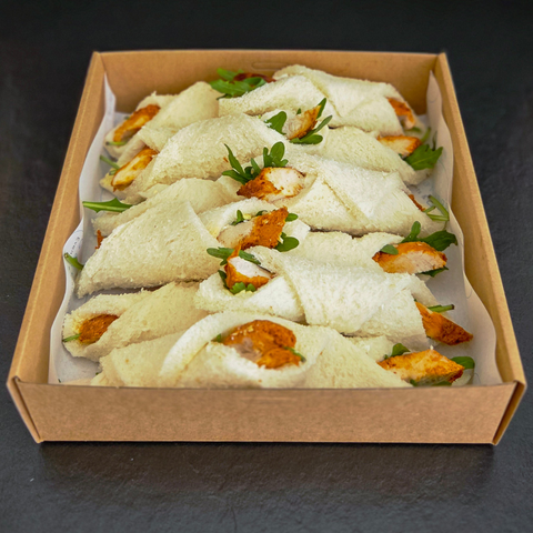 Box of sandwiches with chicken and salad on a dark surface