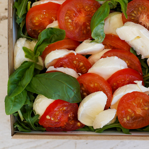 Caprese salad with tomatoes, mozzarella, and basil in a wooden box.