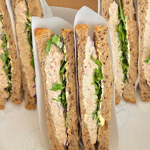 Row of small sandwiches with visible filling on a white surface