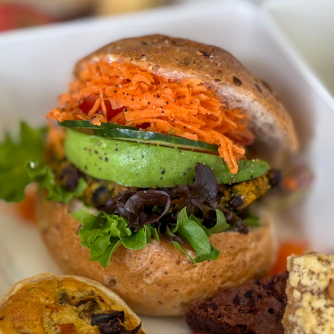 Close-up of a sandwich with carrot, cucumber, and lettuce on a whole grain bun.